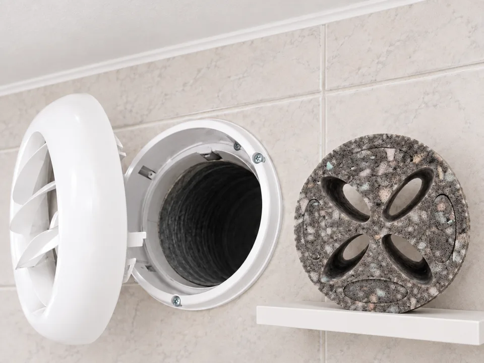 Bouche d'extraction de VMC déposée dans une salle de bain : l'entrée du conduit est dégagée, la mousse Murmure attend sur l'étagère